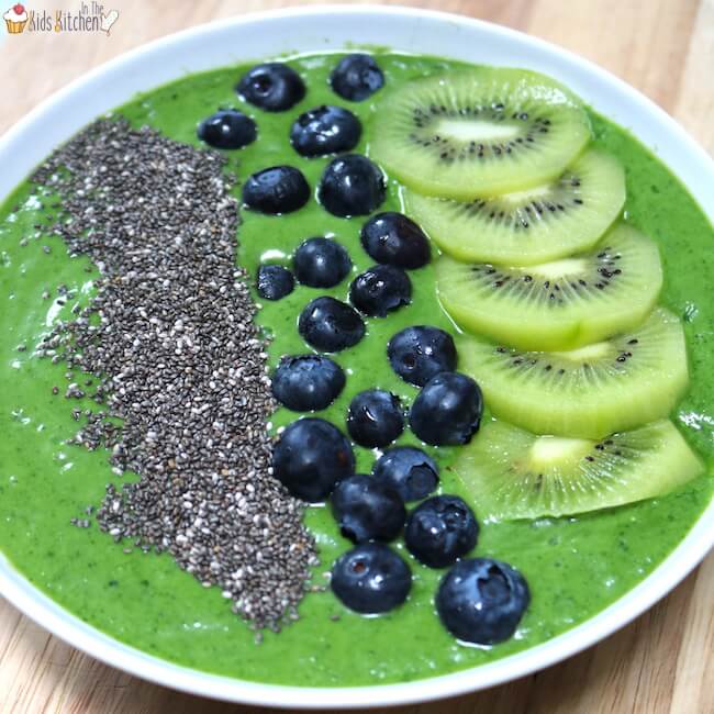 Vibrant green smoothie bowl topped with kiwi slices, blueberries, and chia seeds, a healthy jungle safari animal party food idea