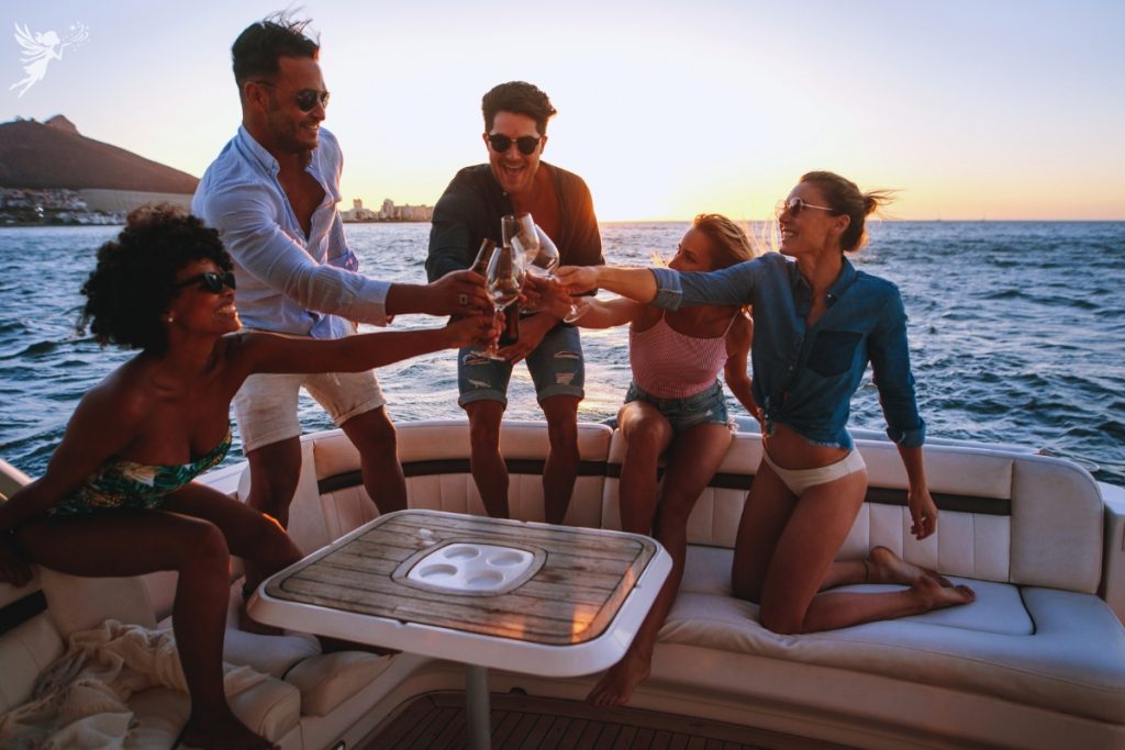 group of friends on boat at sunset toasting summer celebration