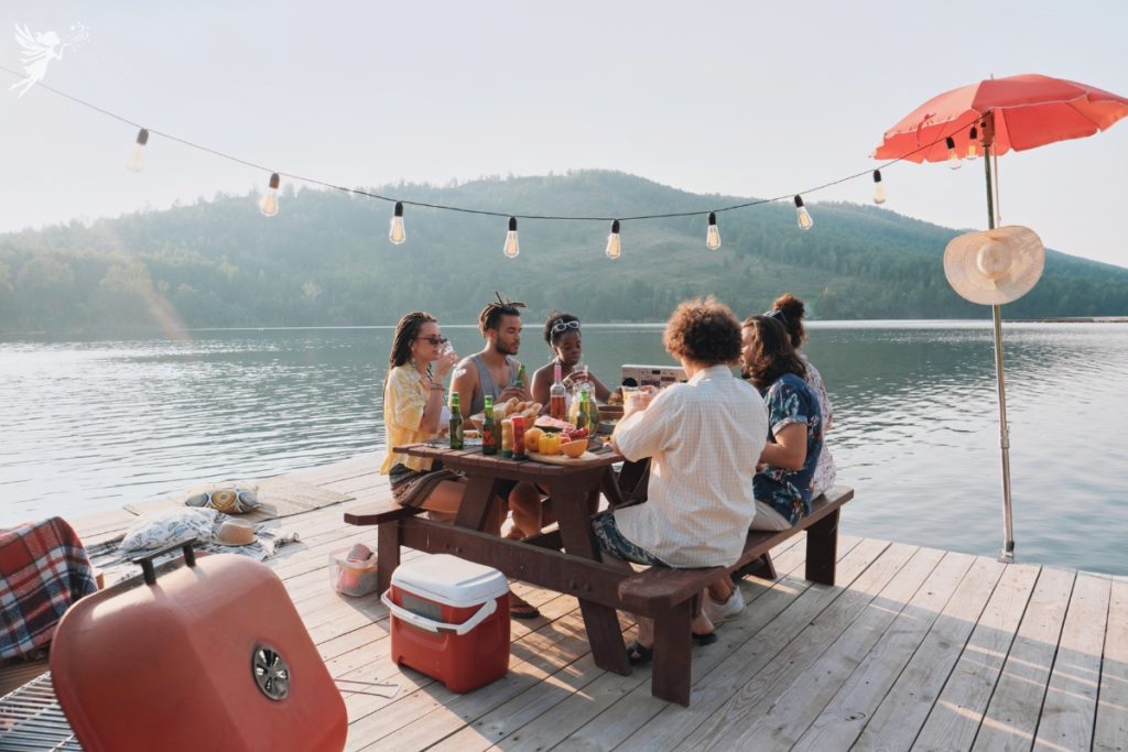 group of friends having picnic next to lake