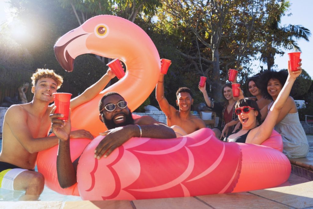 adults floating on giant flamingos in a swimming pool
