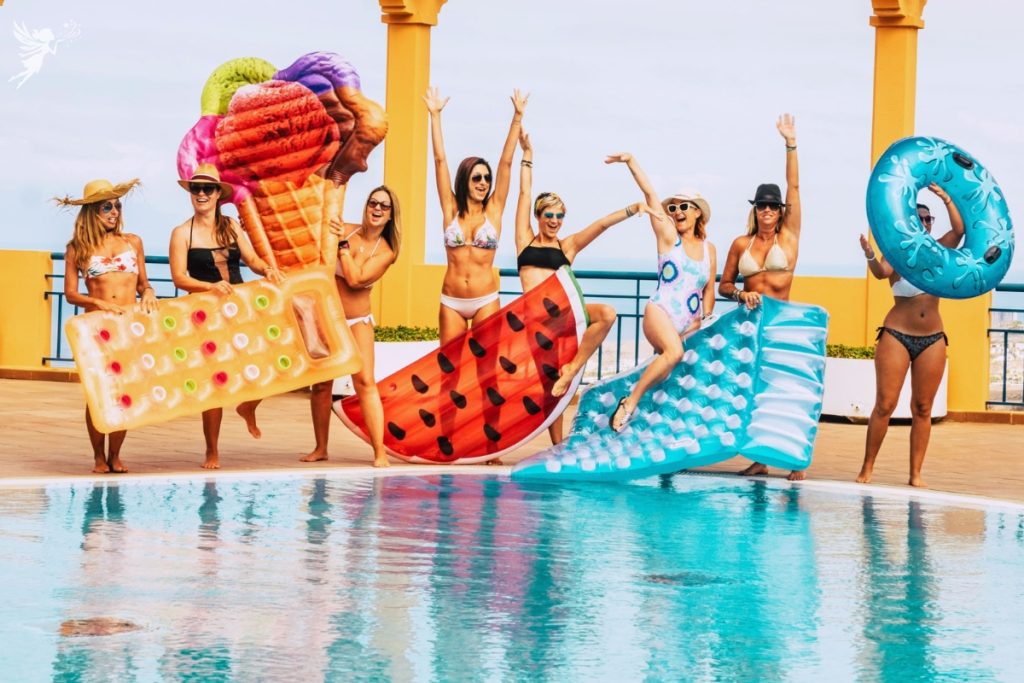 several adults holding oversized novelty pool floaties about to jump in