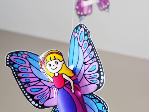 Colorful printable fairy figures hanging from strings as a birthday countdown decoration for fairy party crafts and activities.