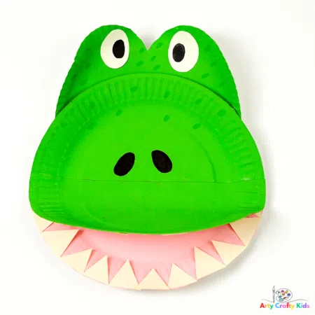 Bright green paper plate crocodile craft with teeth and googly eyes for safari party crafts and activities