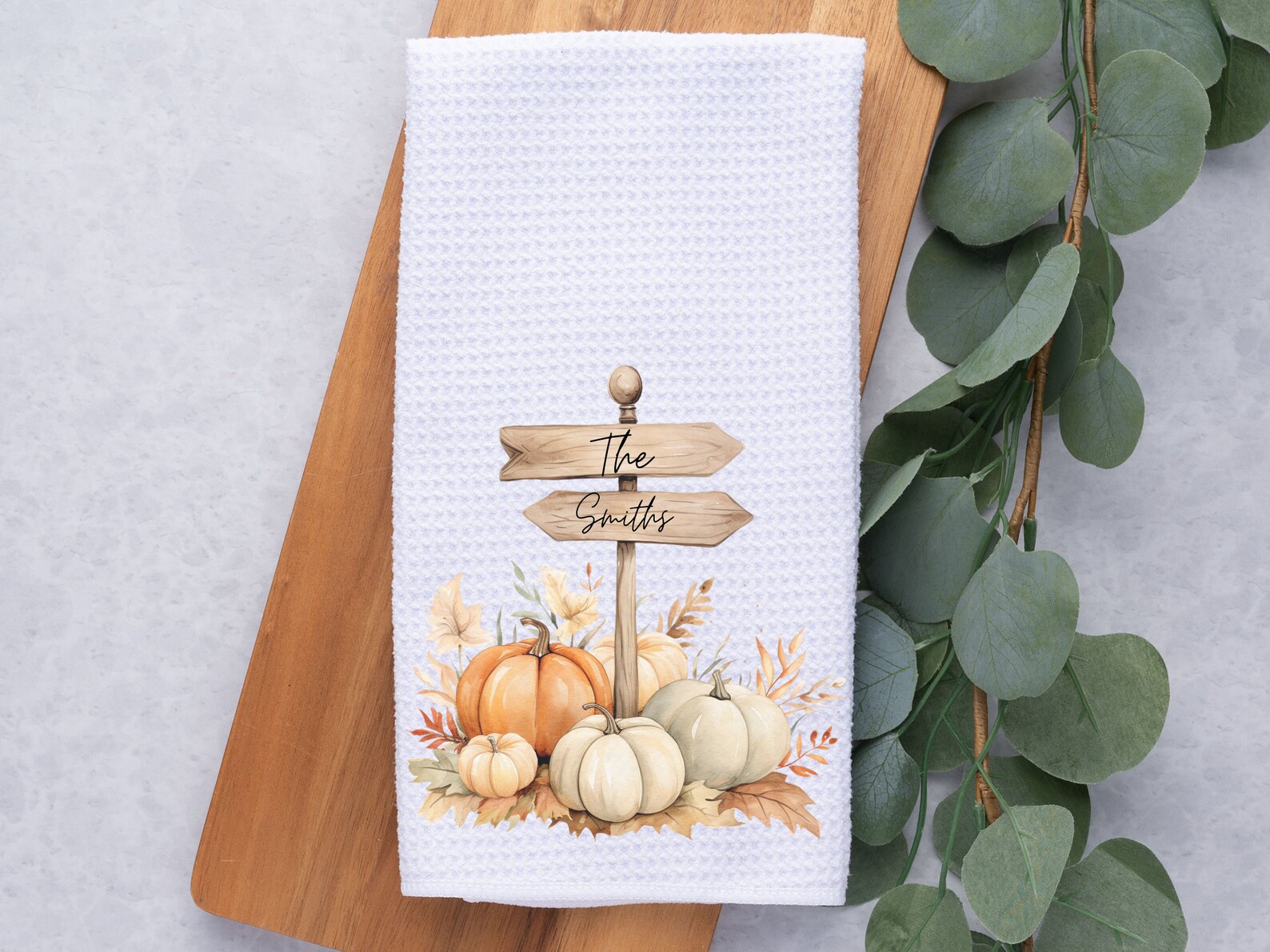 Personalized white waffle kitchen towel with fall pumpkins and family name sign — a charming Thanksgiving hostess gift idea for autumn entertaining.