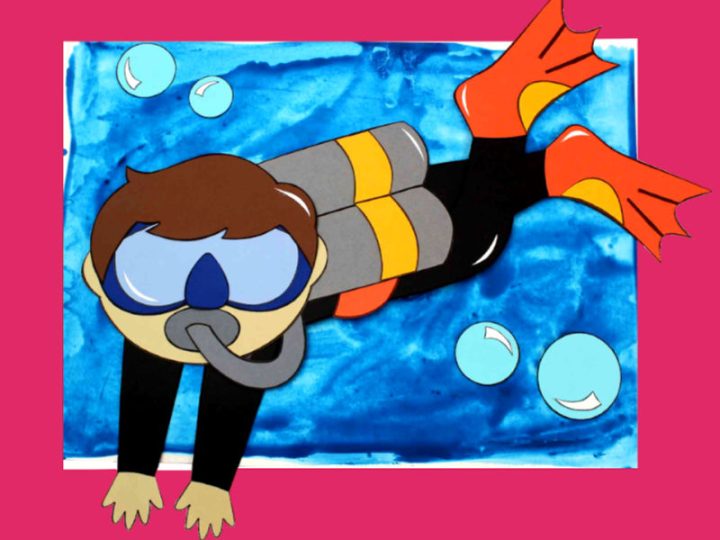 A colorful paper scuba diver craft with goggles and flippers swimming on a blue watercolor painted ocean background