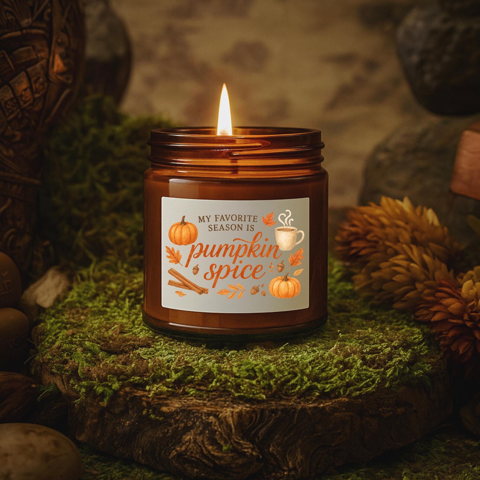 Lit amber jar soy candle labeled 'My Favorite Season is Pumpkin Spice' on a mossy surface — a cozy Thanksgiving hostess gift idea.