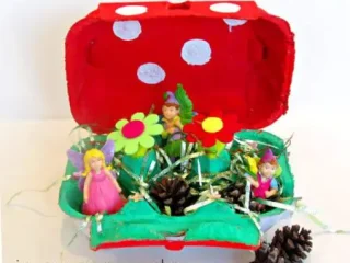 A colorful toadstool fairy garden made from a painted egg carton with fairy figurines, a fun fairy party crafts and activities idea.