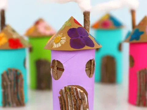 Colorful fairy houses made from painted toilet paper rolls and twigs, a simple and adorable fairy party crafts and activities project.