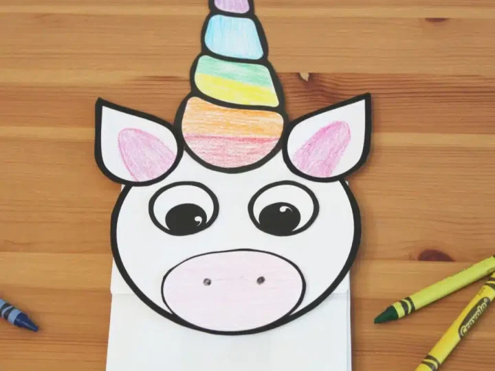 A paper bag unicorn puppet with a rainbow colored horn and big eyes is an easy and adorable unicorn party craft and activity