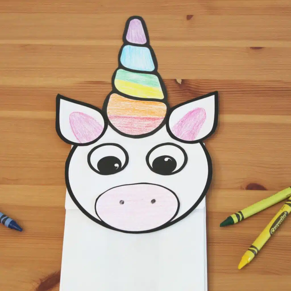 A paper bag unicorn puppet with a rainbow colored horn and big eyes is an easy and adorable unicorn party craft and activity