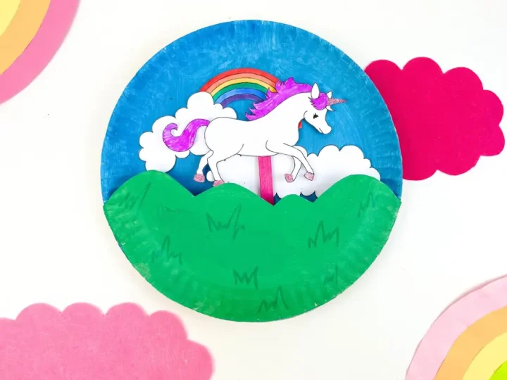 A paper plate unicorn craft with painted blue sky rainbow green hills and a printable unicorn cutout is a classic unicorn party craft and activity