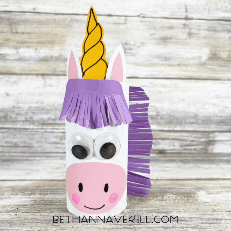 A toilet paper roll unicorn with purple fringe mane and gold glitter horn makes a fun unicorn party craft and activity for kids