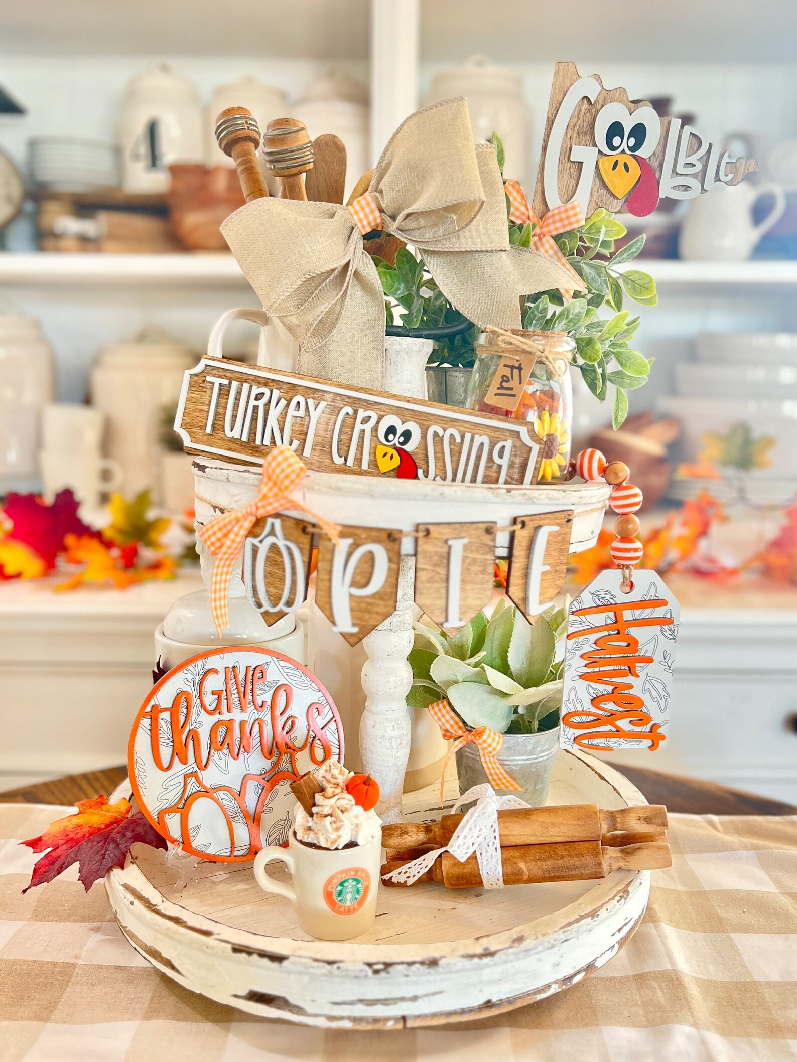 Rustic white distressed tiered tray decorated with turkey signs, 'Give Thanks' rounds, and fall accents — a festive Thanksgiving hostess gift idea for holiday home decor.