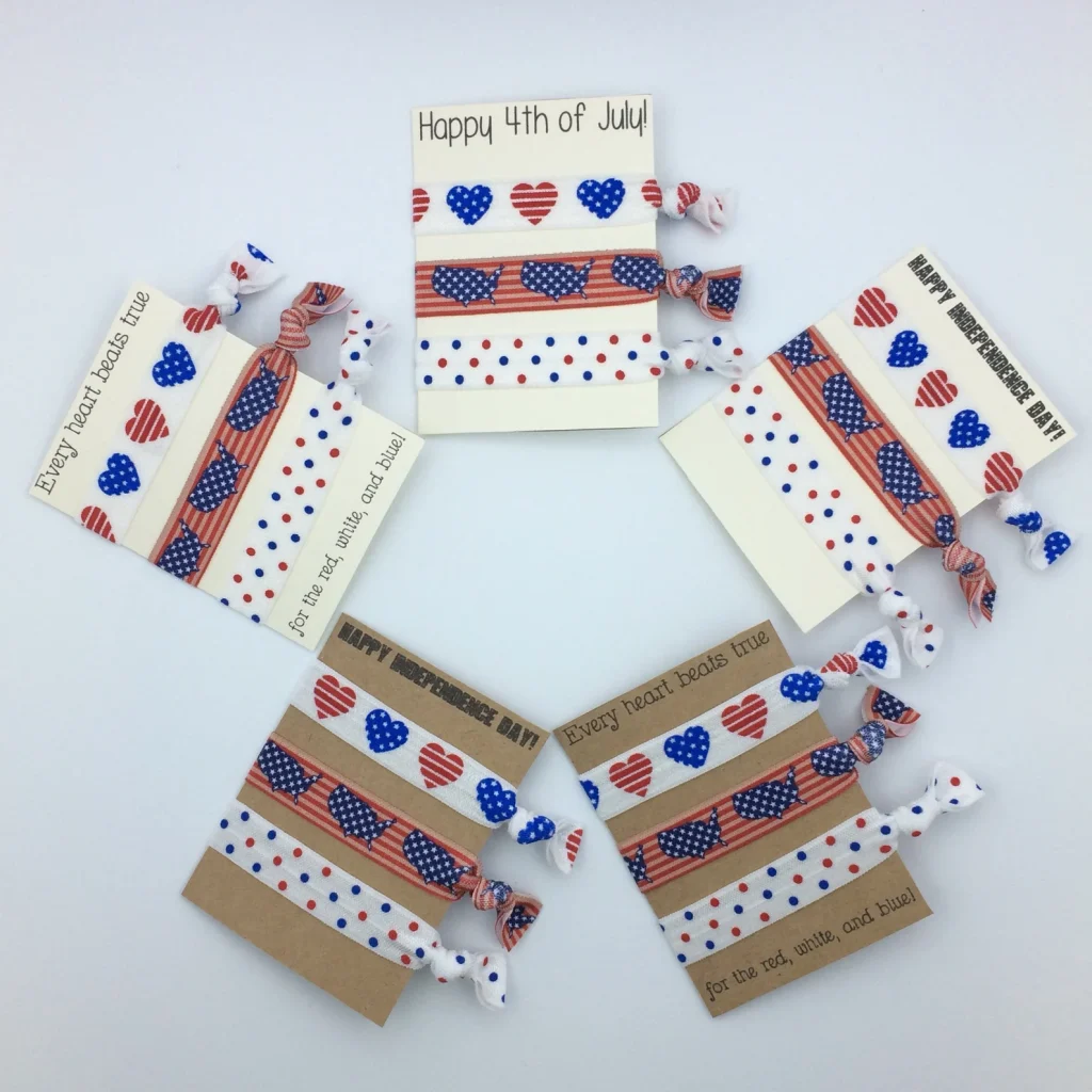 Five sets of red white and blue patriotic hair ties with hearts and dots patterns on Happy Independence Day greeting cards, charming 4th of July party favors.