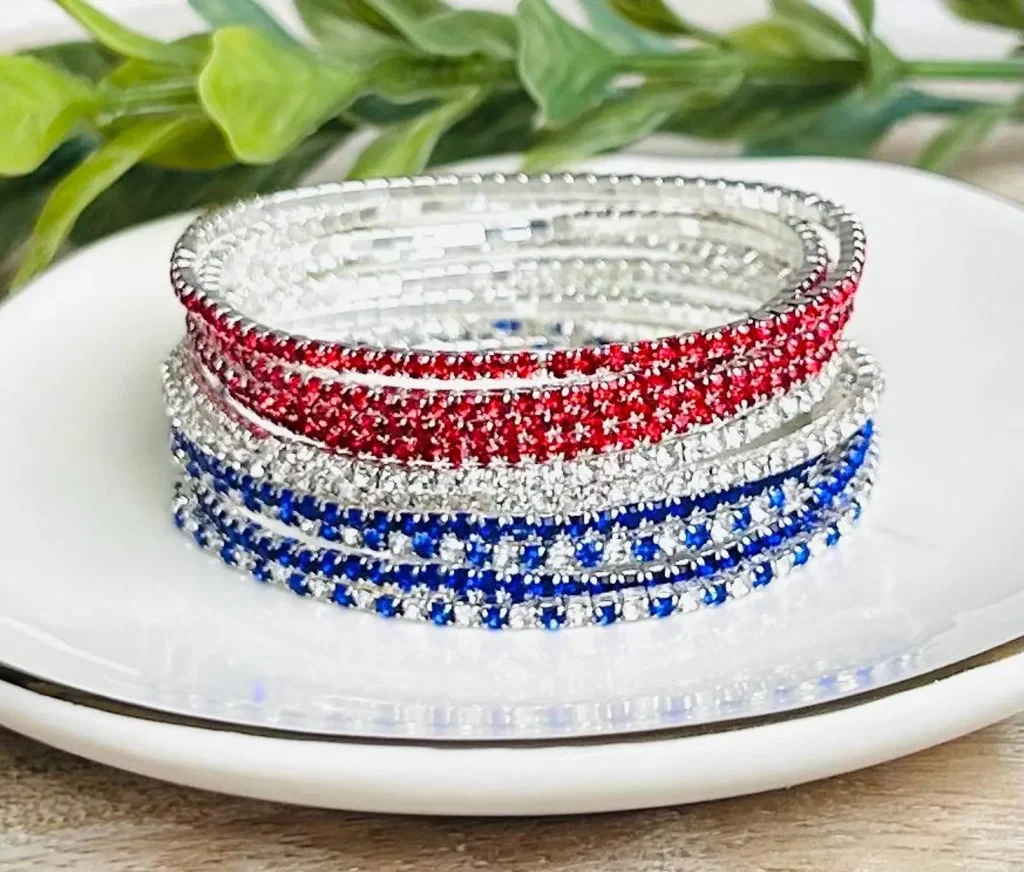 Stacked red, silver, and blue rhinestone stretch bracelets in patriotic colors displayed on a white plate, sparkling 4th of July party favors.