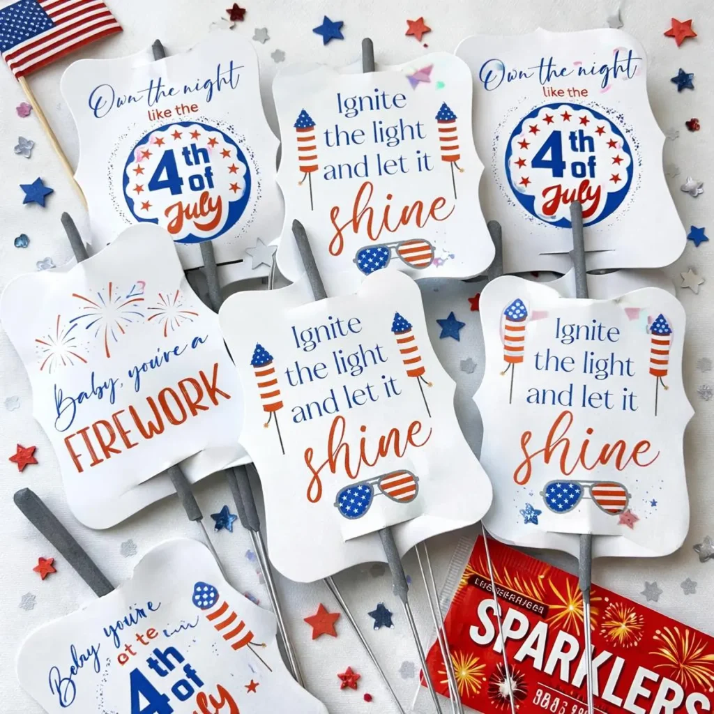 Six patriotic sparkler tags with firework and Independence Day sayings scattered among red white and blue star confetti, creative 4th of July party favors.