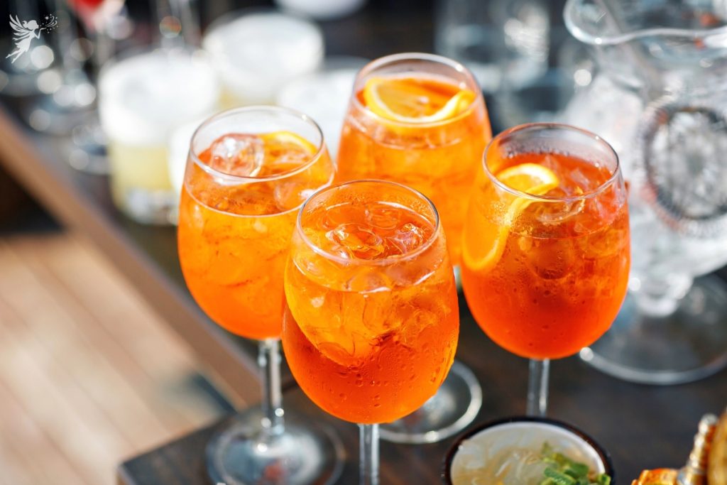 4 glasses of aperoal drink with garnish on a serving tray waiting to be served
