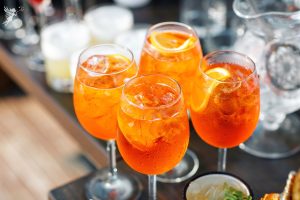 4 glasses of aperoal drink with garnish on a serving tray waiting to be served