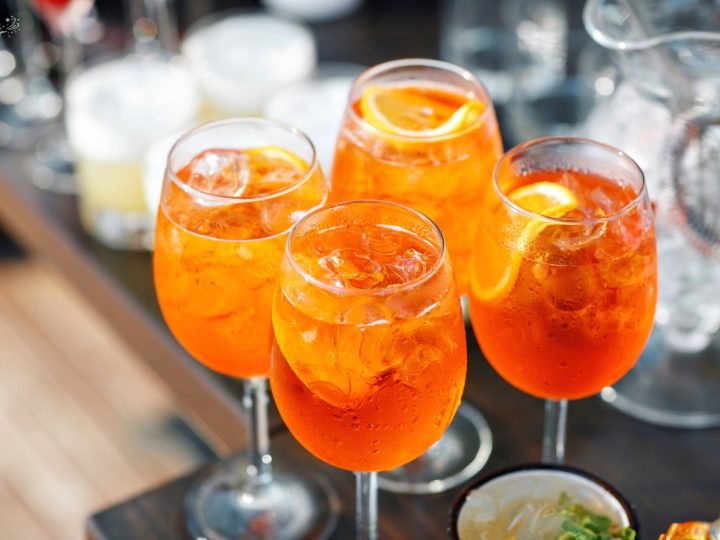 4 glasses of aperoal drink with garnish on a serving tray waiting to be served