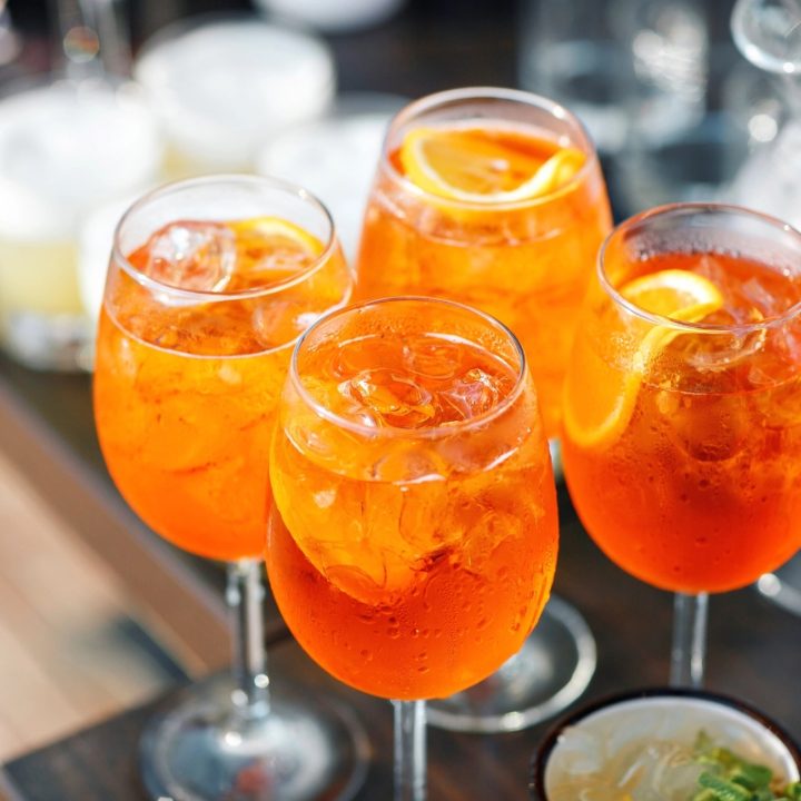 4 glasses of aperoal drink with garnish on a serving tray waiting to be served