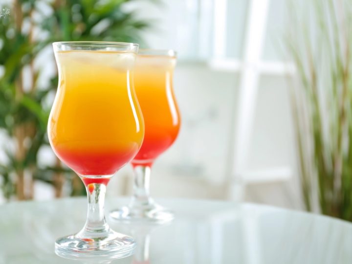 two glasses of non-alcoholic sunrise orange juice and grenadine drink on a kitchen counter