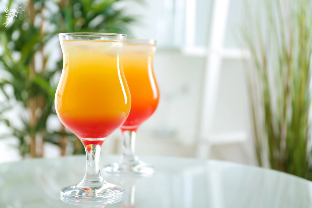 two glasses of non-alcoholic sunrise orange juice and grenadine drink on a kitchen counter