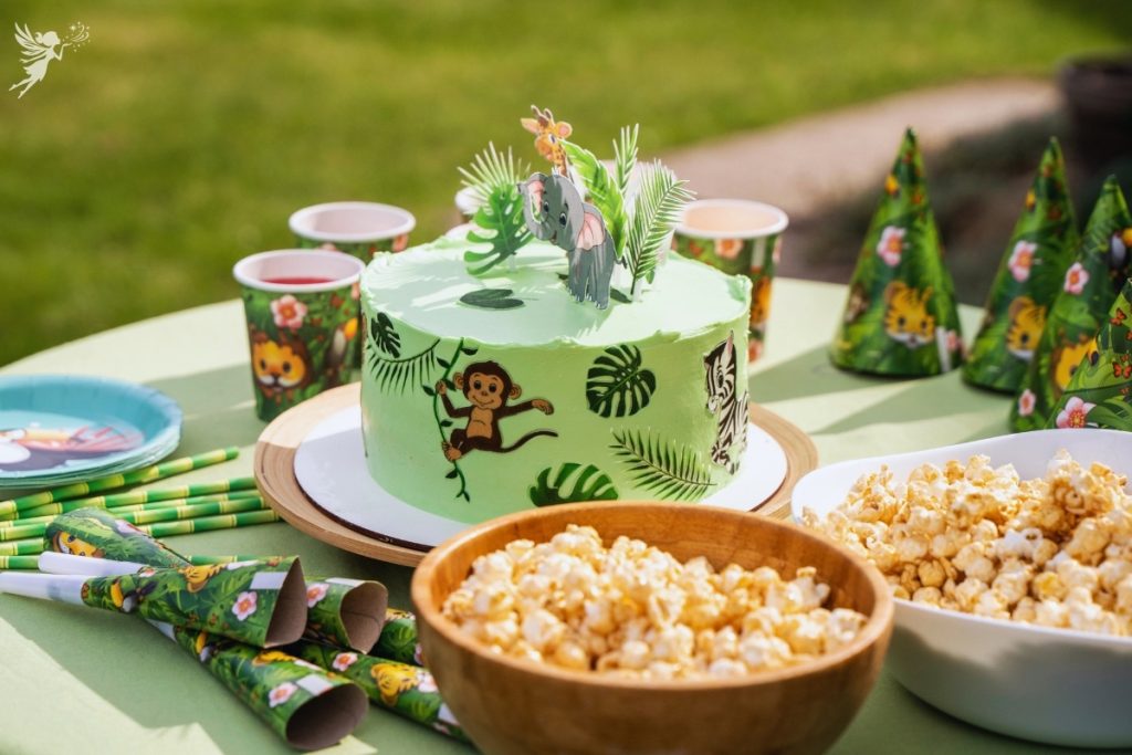 a green cake decorated with monkeys and decorated table with a jungle animal theme