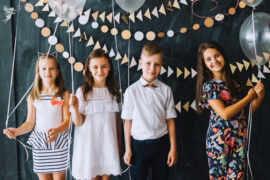 group of tween boys and girls with blackboard background, streamers and balloons