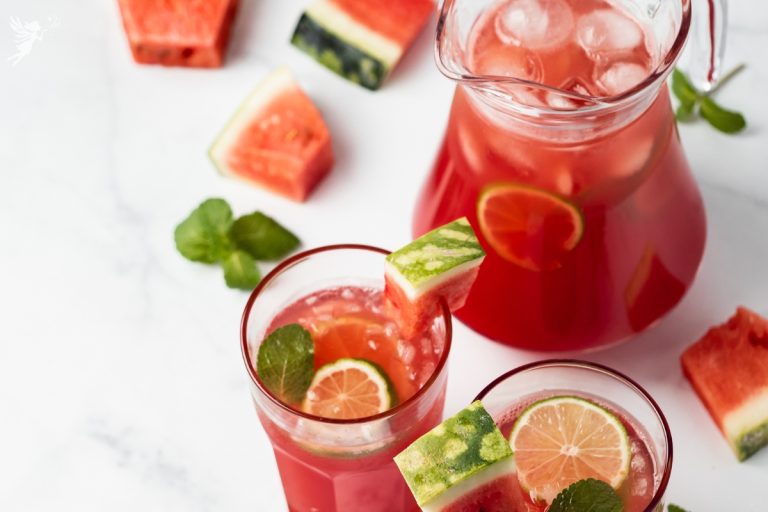 close uo overview of a glass and a cocktail pitcher filled with watermelon mint cooler mocktail