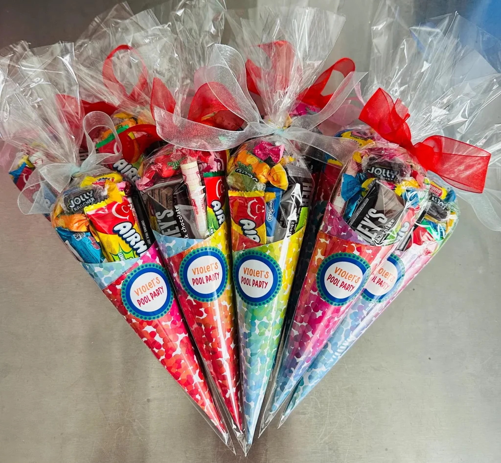 Personalized colorful candy cones filled with Jolly Ranchers, Airheads, and Hershey's chocolates tied with ribbon bows — sweet and festive tween girl party favors.