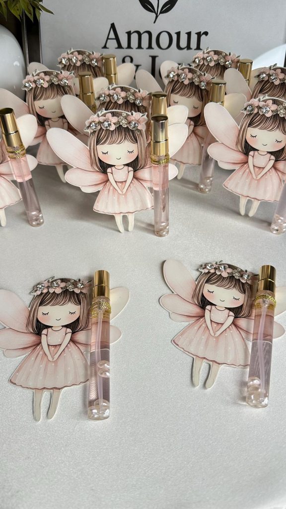 Mini perfume roller bottles paired with illustrated pink fairy girl cutouts wearing floral crowns and butterfly wings arranged as delightful fairy party favors for a girls birthday party