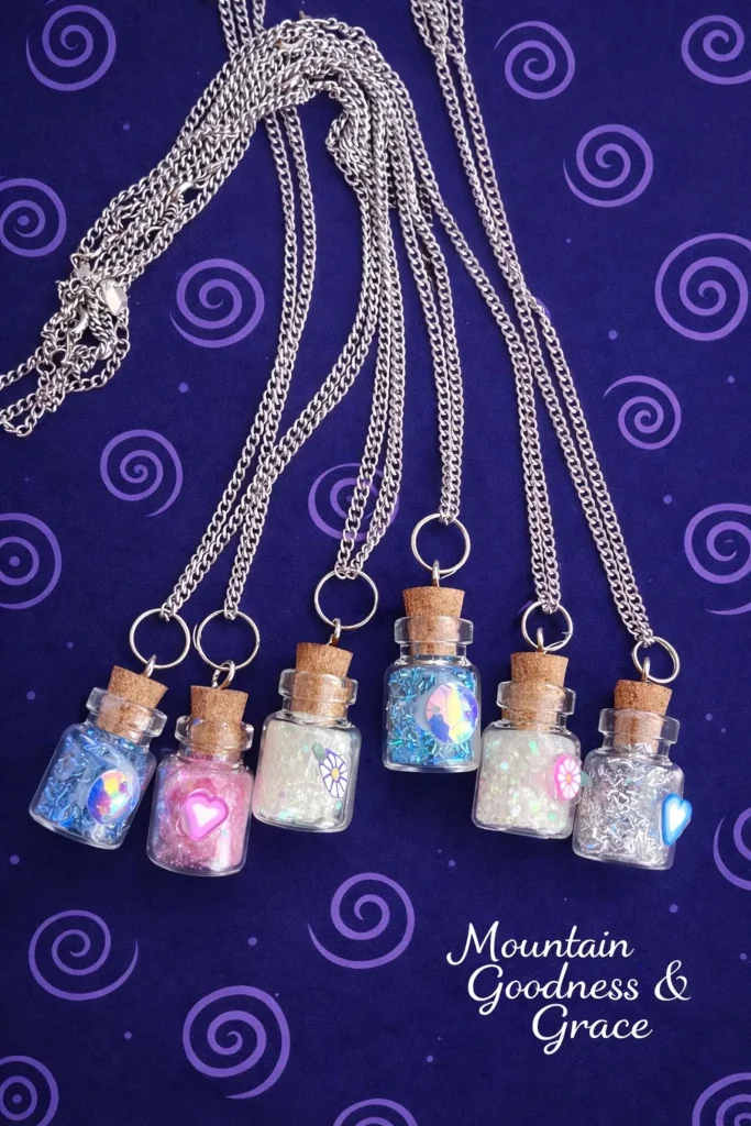 Six mini corked glass bottle necklaces filled with colorful glitter and holographic heart and star charms on silver chains make enchanting fairy party favors for girls