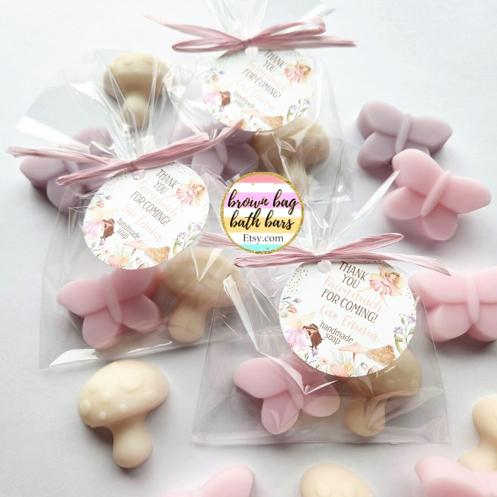 Clear cellophane bags filled with mushroom and butterfly shaped handmade soaps in soft pink and cream tones tied with pink ribbon bows make charming fairy party favors for a girls birthday celebration