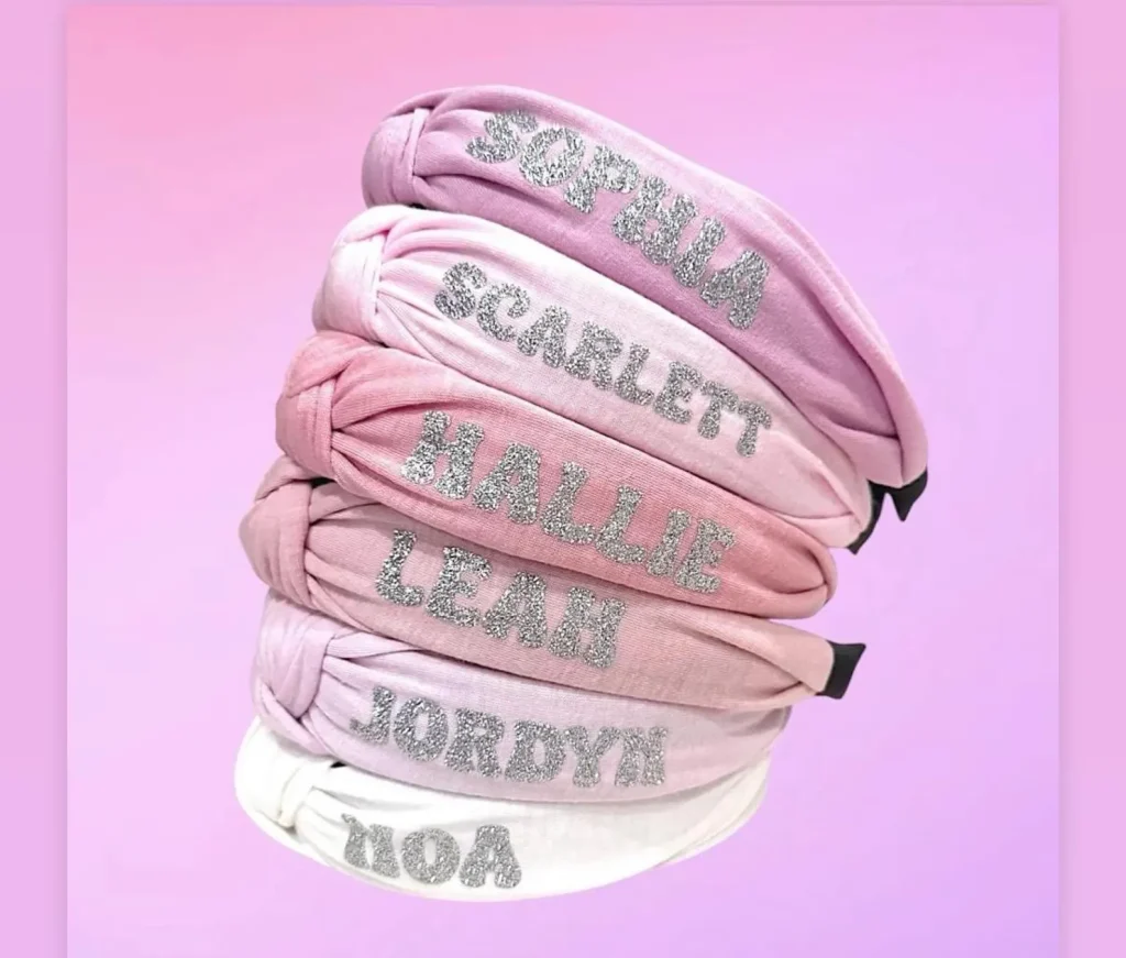 Stacked personalized knot headbands in shades of pink and white with silver glitter names, making stylish and memorable tween girl party favors.