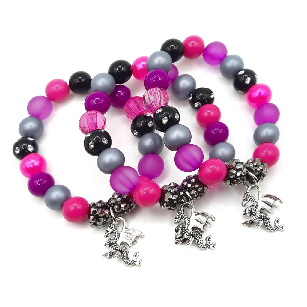 Three beaded stretch bracelets in hot pink, purple, gray, and black with silver dragon charms and rhinestone accents — edgy tween girl party favors.