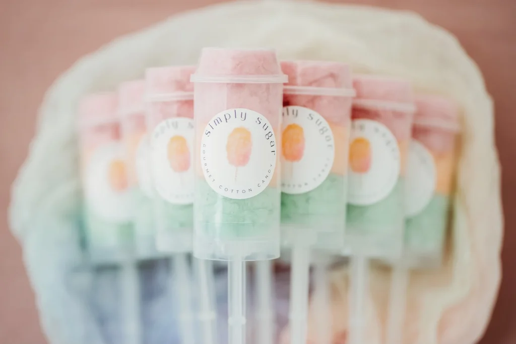 Pastel rainbow layered cotton candy push-pop tubes with "Simply Sugar Gourmet Cotton Candy" labels, making dreamy and delicious tween girl party favors.