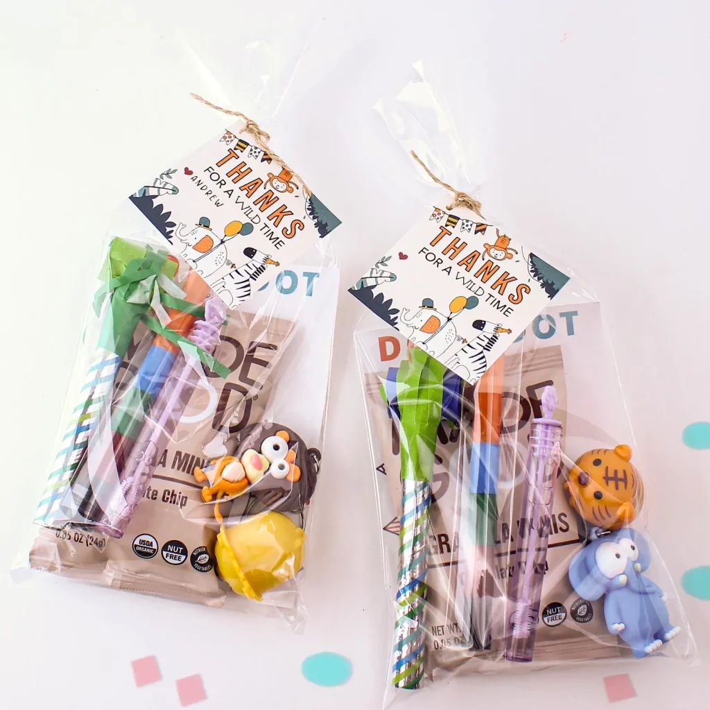 Safari animals party favor ideas featuring clear goodie bags filled with animal figurine keychains, pencils, bubbles, and snacks, tied with twine and personalized "Thanks for a Wild Time" tags.