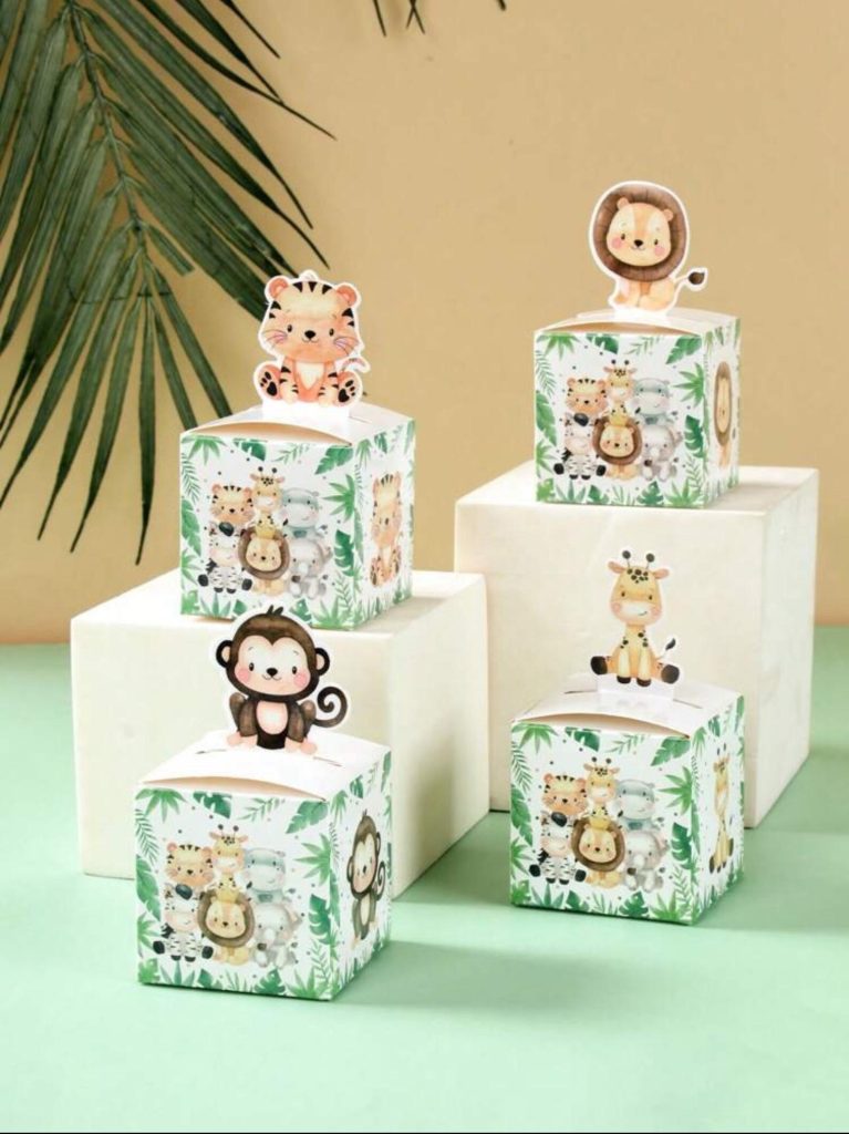 Safari animals party favor ideas featuring white square treat boxes decorated with tropical leaf prints and cute 3D tiger, lion, monkey, and giraffe animal toppers.
