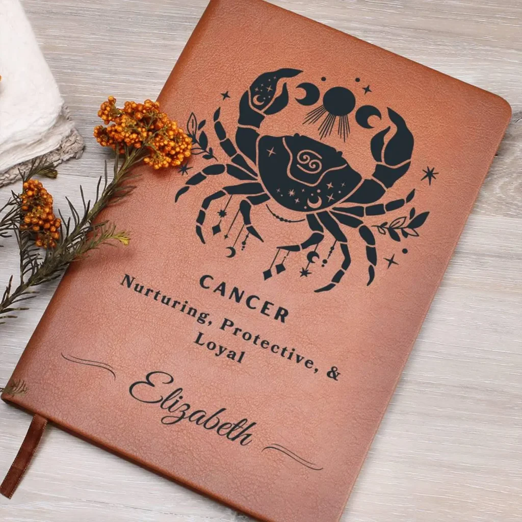 A tan leather journal personalized with a celestial Cancer crab illustration and a name, a beautiful and meaningful July birthday gift idea.