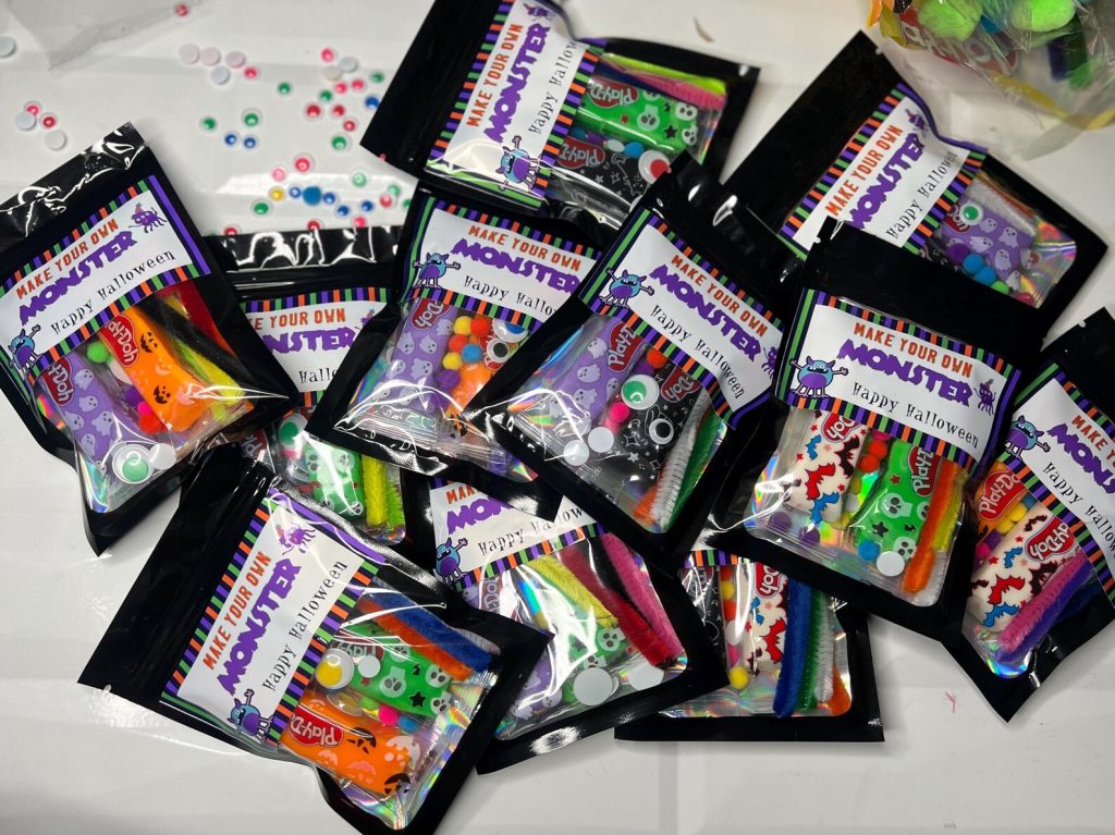 Make-your-own monster craft packs with Play-Doh, pipe cleaners, and googly eyes, colorful DIY Halloween party favors for kids.