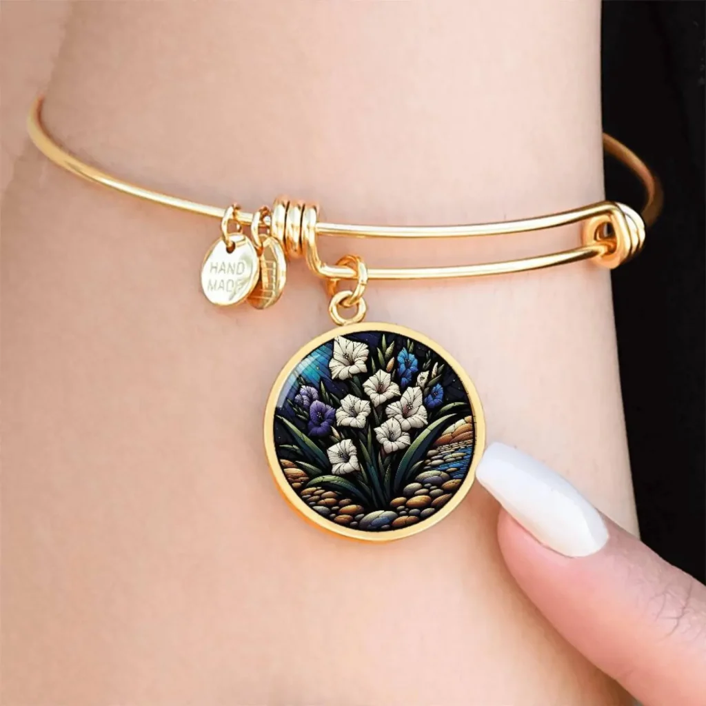 A gold adjustable bangle bracelet with a round gladiolus mosaic art charm, a beautiful and wearable August birthday gift idea.