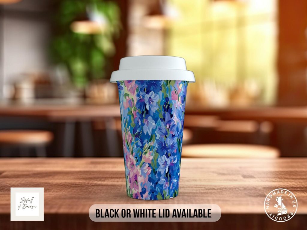 A reusable travel mug covered in a vibrant blue and pink larkspur floral pattern with a white lid, a pretty and practical July birthday gift idea.