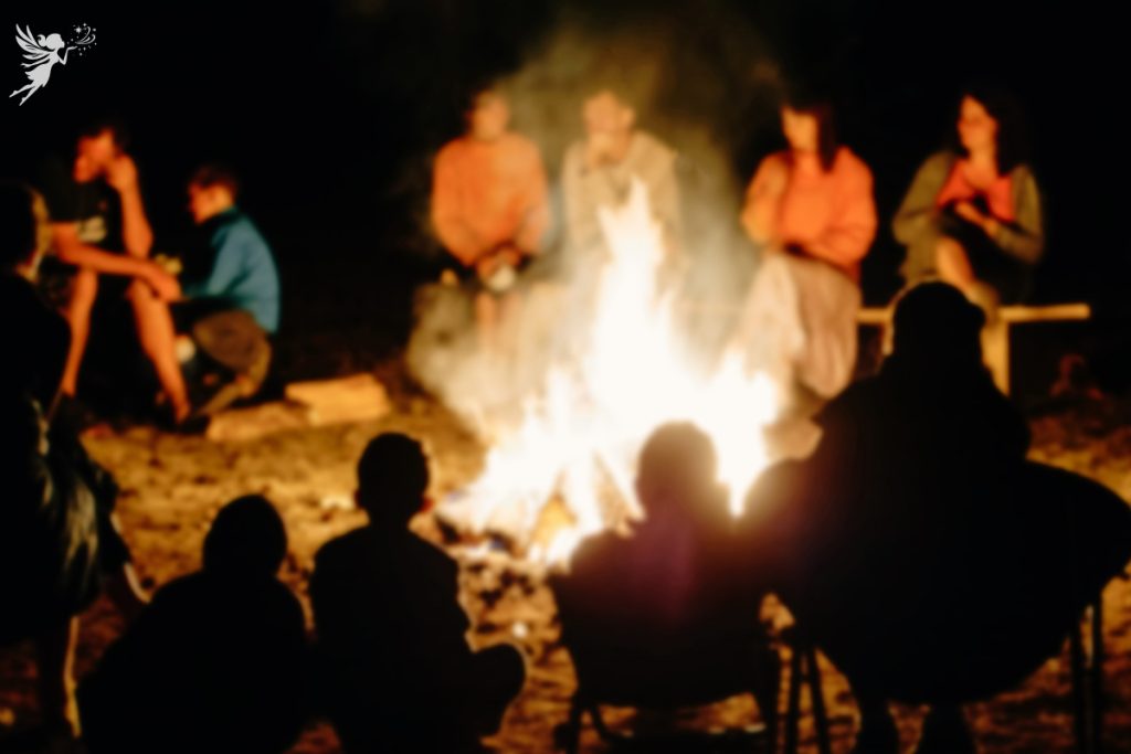 teenages and family sitting around a bonfire mood lighting slightly blurred party