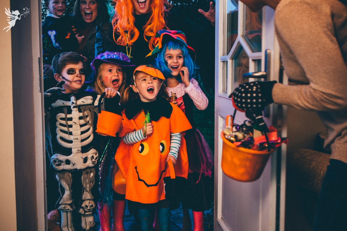 mother opening door to trick or treating children with a bucket of goodies other than candy