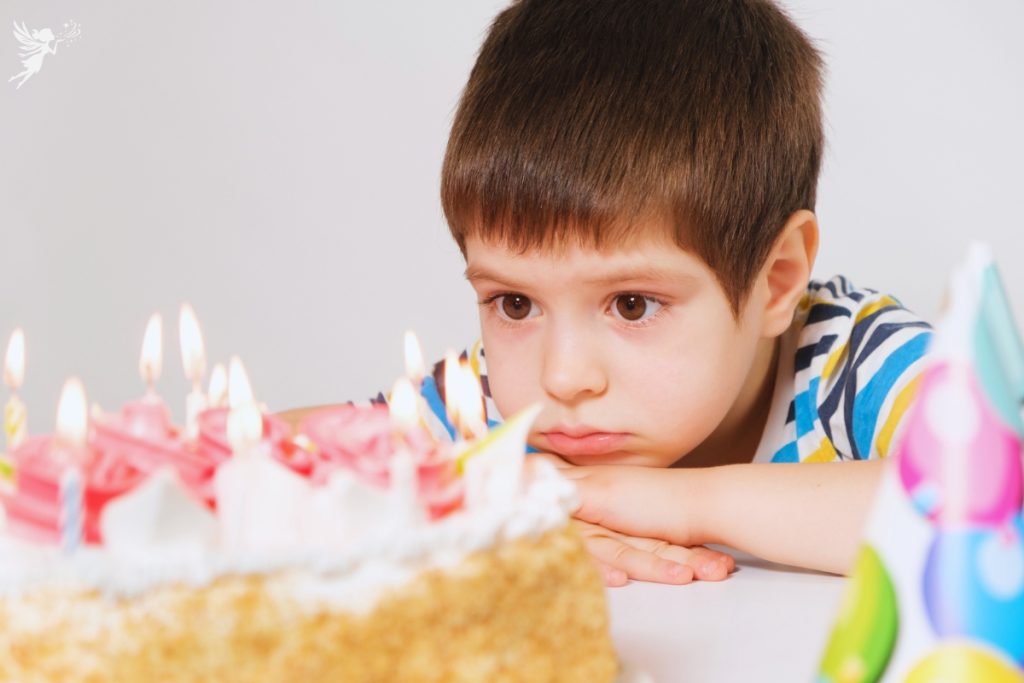 shy child with candles birthday cake hiding behind it