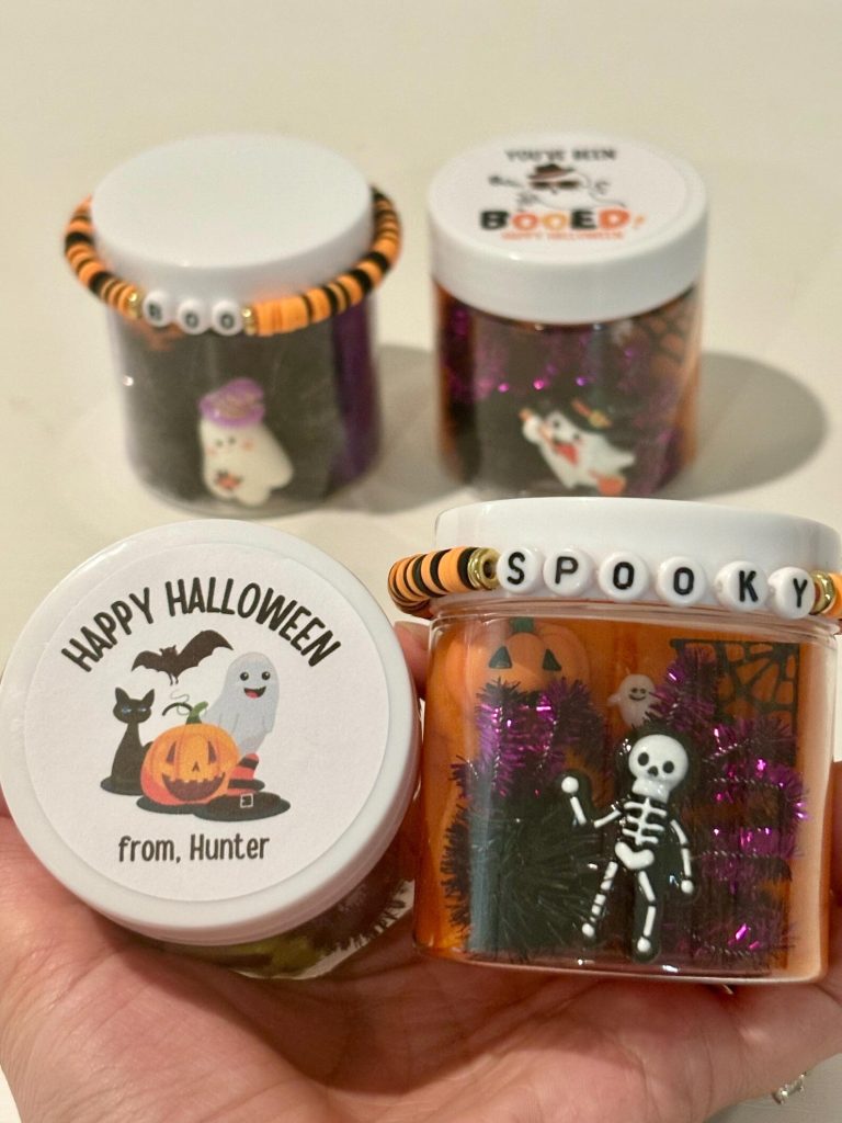 Personalized Halloween slime jars with beaded "Boo" and "Spooky" bracelets, festive Halloween party favors for a spooky celebration.