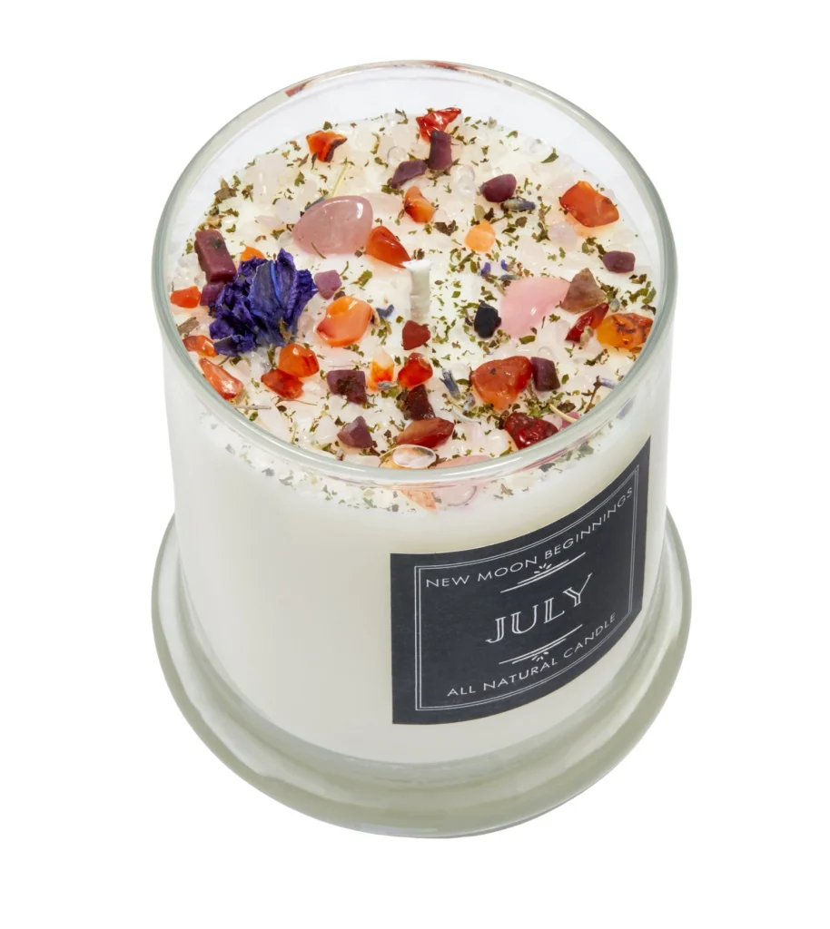 A white soy candle topped with colorful crystal chips, dried botanicals and rose quartz, a luxurious and spiritual July birthday gift idea.