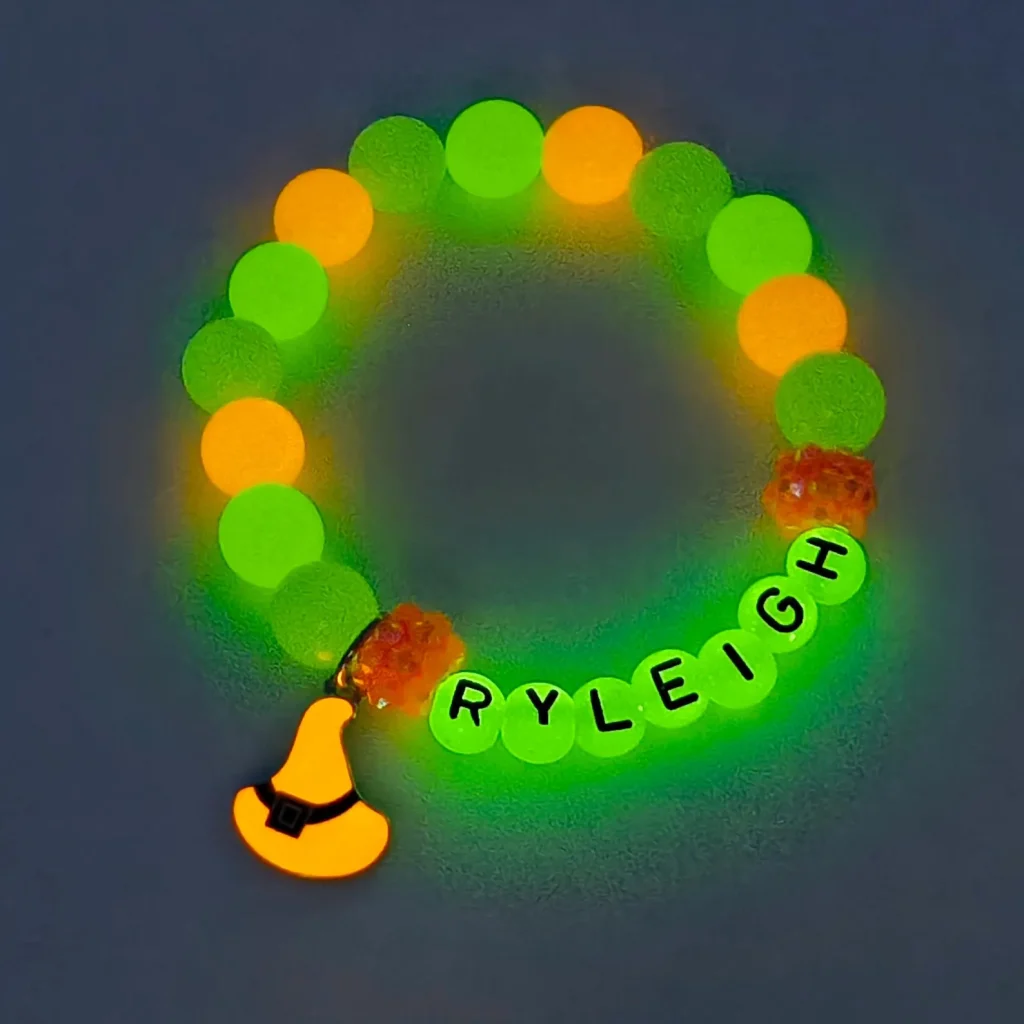 Glow-in-the-dark personalized name bracelet with a witch hat charm, a fun glowing addition to Halloween party favors.