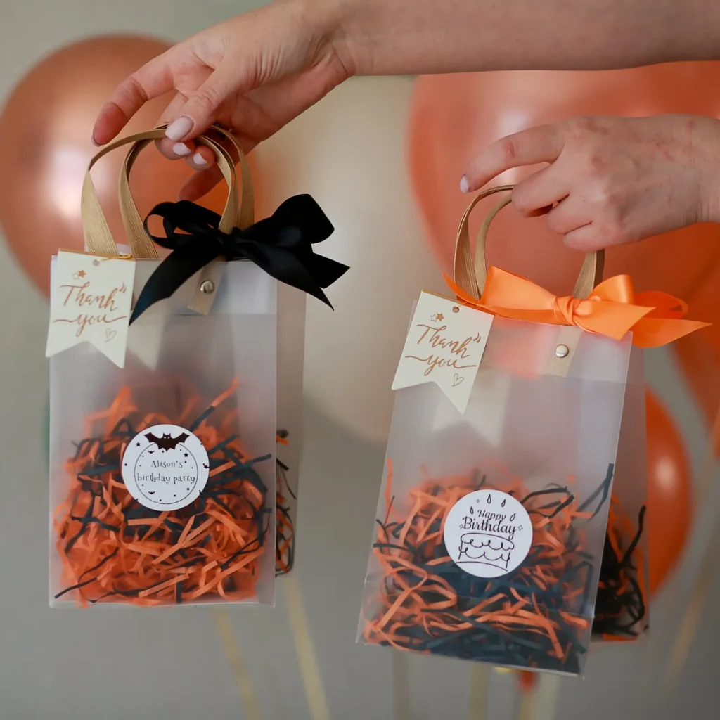 Clear gift bags with bow accents and personalized thank-you tags, an elegant way to package Halloween party favors.