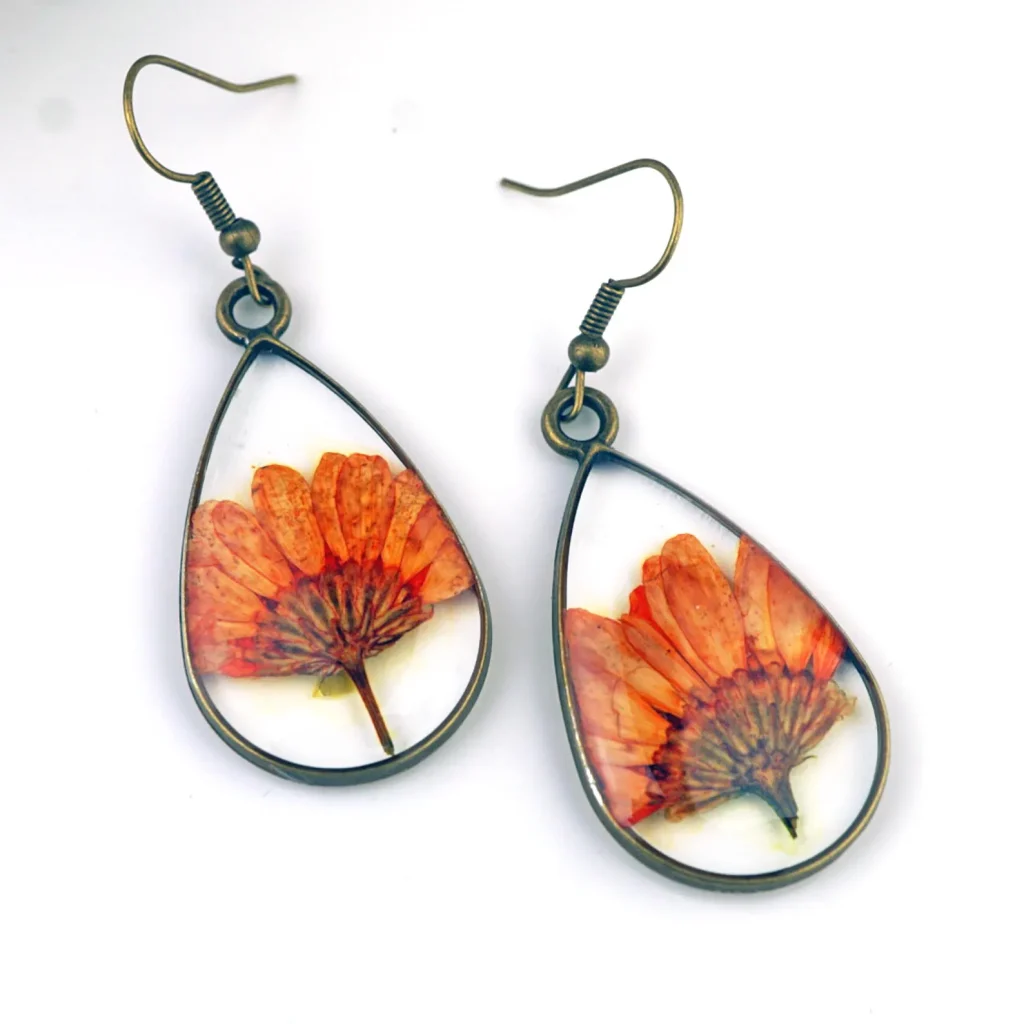 Bronze teardrop earrings encasing real pressed orange chrysanthemum flowers in clear resin, a unique and botanical November birthday gift idea.